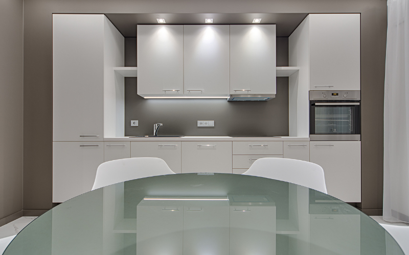 a white kitchen with a glass table and white cabinets