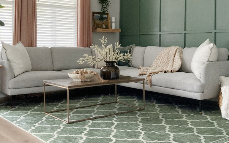 a green coloured rug with a couch with a vase of flowers on a coffee table