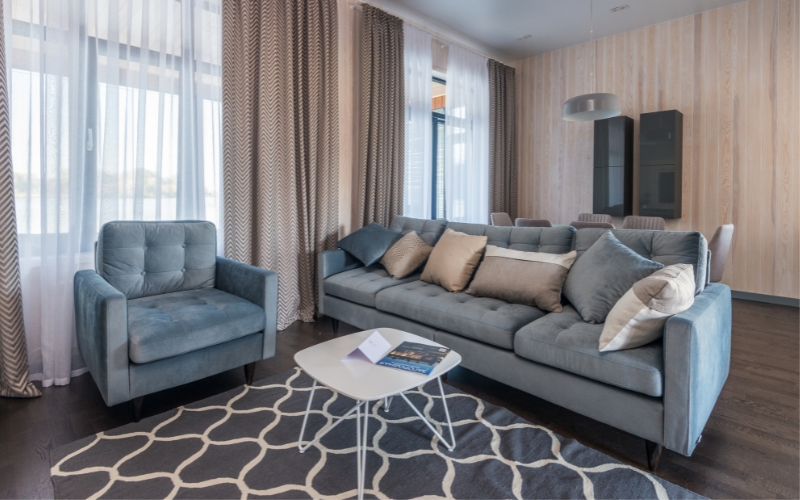 a living room with couches and a coffee table resting on a patterned grey rug