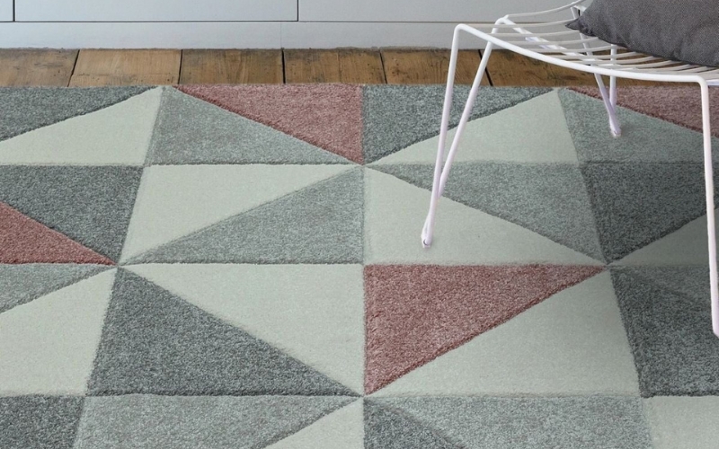 a white chair on a diamond pattern rug in pink and grey 