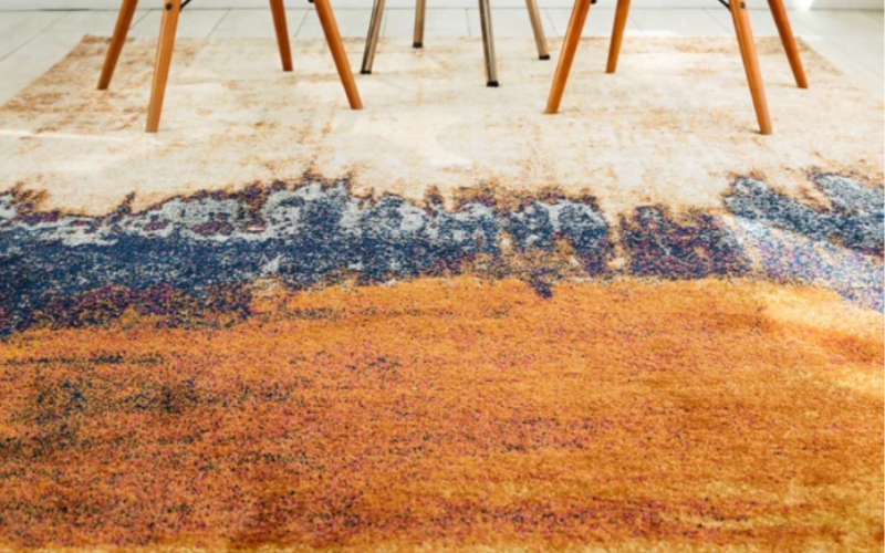 a close up of an orange blue and cream rug