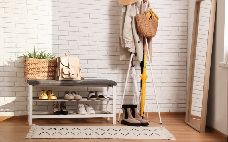 a coat rack with shoes and umbrellas and small runner rug