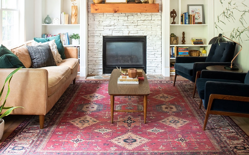 a living room with a fireplace and a coffee table resting on red persian rug