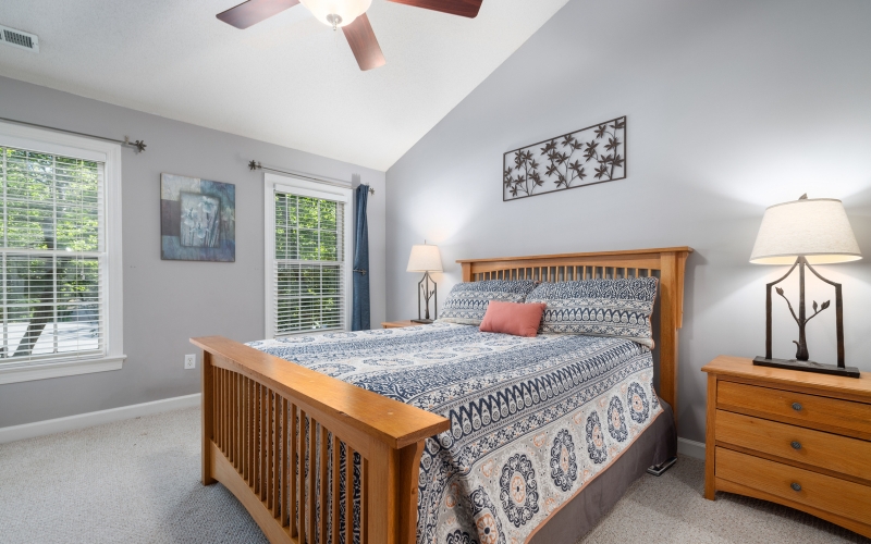 a bedroom with a wooden bed and a ceiling fan